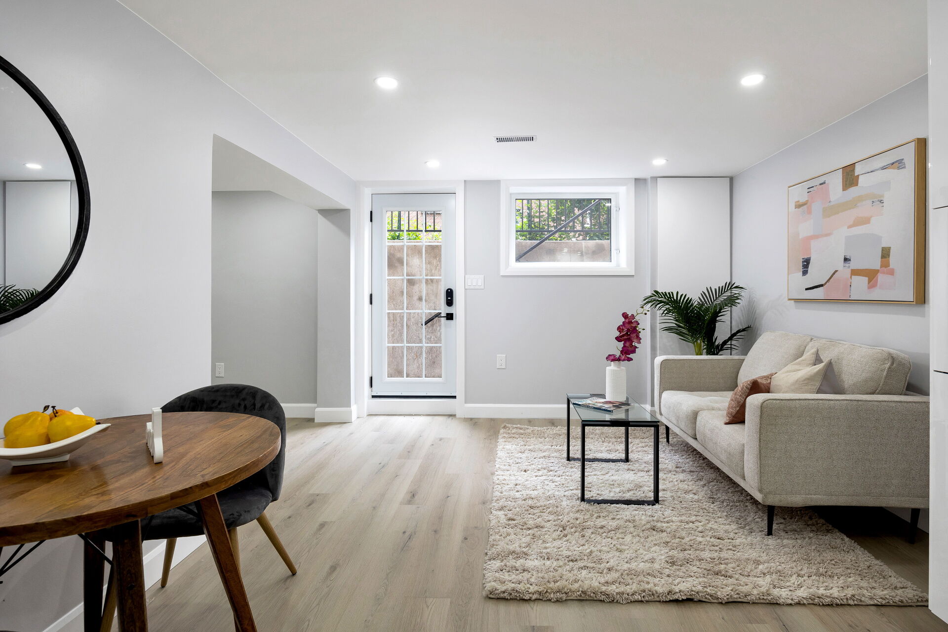 Open-concept lower-level studio living area with private entrance and large window.