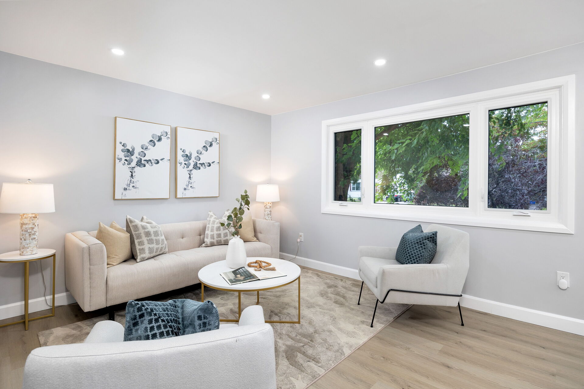 Upper-unit living room with a large picture window overlooking mature trees.