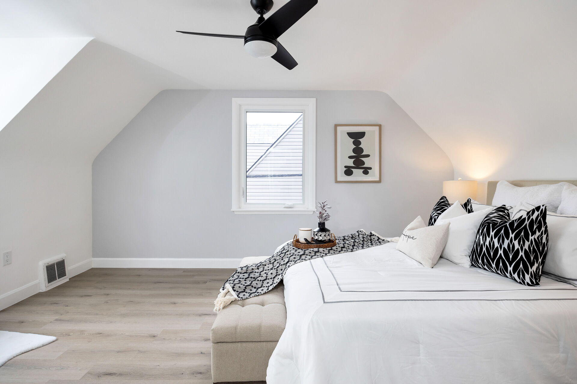 Primary bedroom with sloped ceiling, ceiling fan and a king bed.